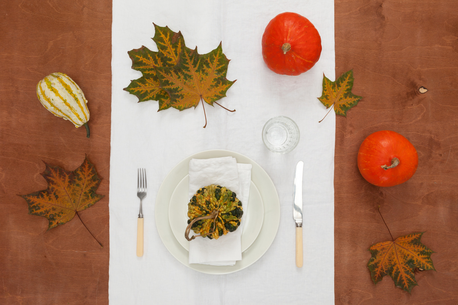Autumn table setting with maple leaves and pumpkin