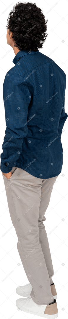 Vue arrière d'un homme en vêtements décontractés debout avec les mains dans les poches