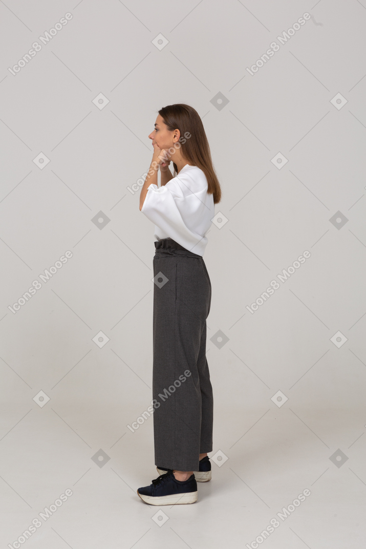 Vista lateral de una señorita haciendo muecas en ropa de oficina