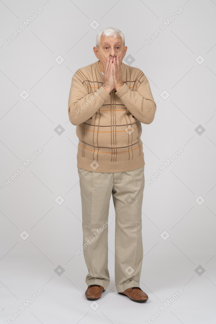 Vorderansicht eines beeindruckten alten mannes in freizeitkleidung, der den mund mit den händen bedeckt