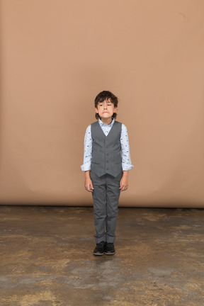 Front view of a boy in suit looking at camera and making faces