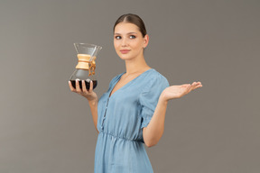 Three-quarter view of a young woman in blue dress holding a pitcher of wine