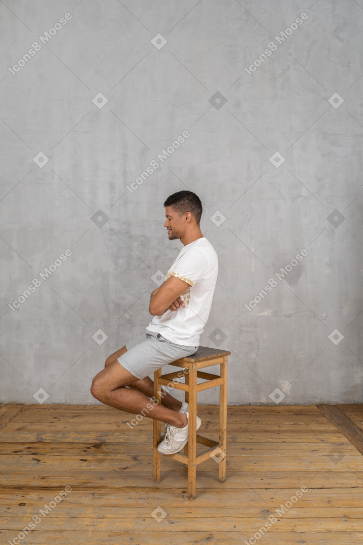 Vista lateral do homem sentado com os braços cruzados