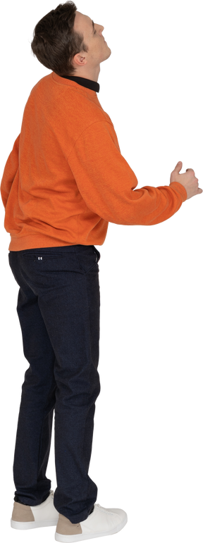 Молодой человек в оранжевой толстовке позирует