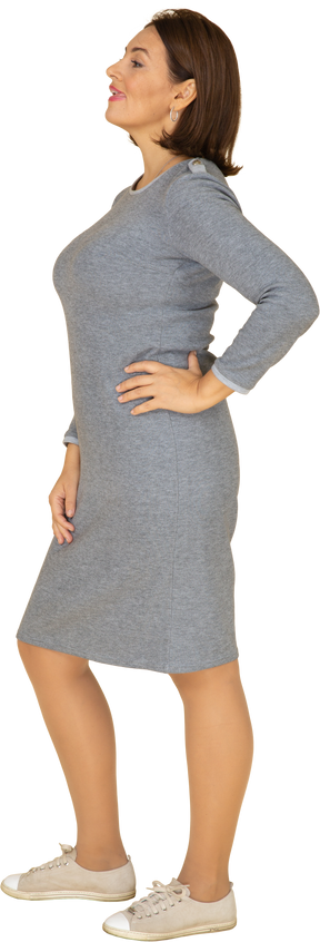 Vista laterale di una donna in abito grigio in posa con la mano sull'anca