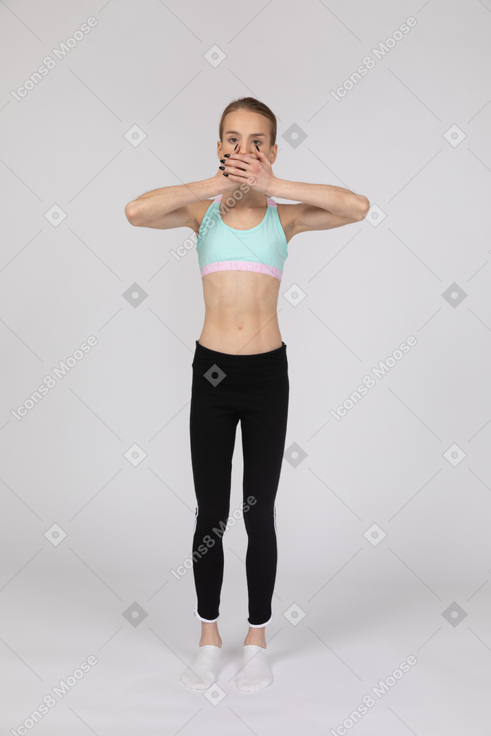 Una adolescente con ropa deportiva tapándose la boca con las manos.