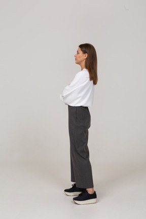 Vista lateral de uma jovem descontente com roupas de escritório, cruzando os braços