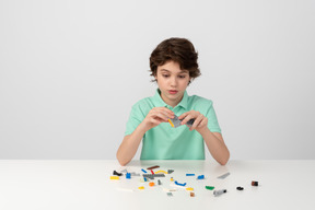 Menino de camisa pólo verde brincando com blocos de construção