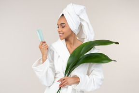 Black woman in white bathrobe and head towel enjoying her skin care routine