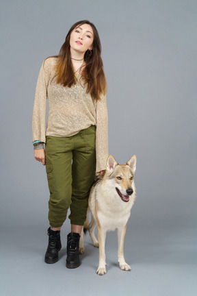 Pleine longueur d'un maître féminin debout près de son chien et regardant la caméra