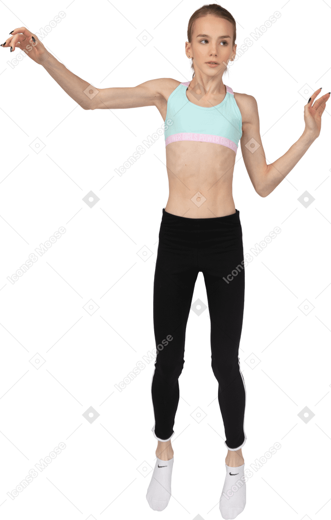 一个年轻的女孩，穿着运动衣的前视图举起手，一边跳跃时放在一边