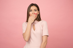 Fille avec une expression de choc sur son visage, tenant son poignet à côté de sa bouche