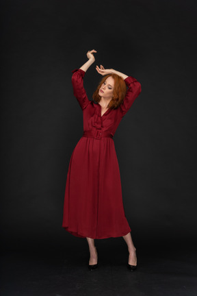 Young ginger lady in red dress spreading arms
