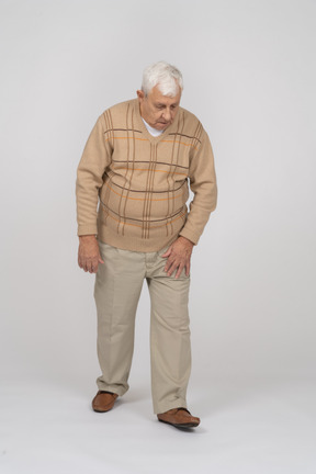 Vue de face d'un vieil homme en vêtements décontractés marchant vers l'avant et regardant vers le bas
