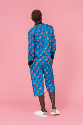 Black man in blue pajamas standing on the pink background