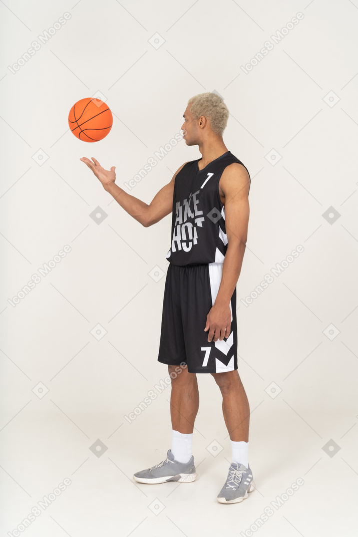Vista de três quartos de um jovem jogador de basquete jogando uma bola