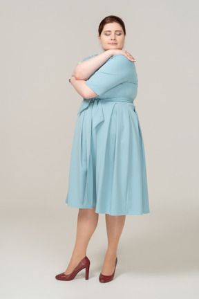 Vista frontal de uma mulher de vestido azul se abraçando
