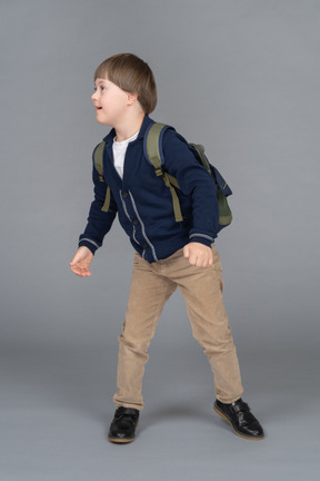 Niño pequeño con una mochila girando hacia un lado