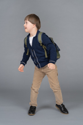 Little boy with a backpack turning to the side