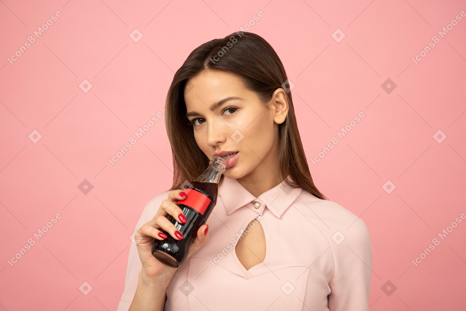 Attractive young girl holding a glass bottle close to her mouth
