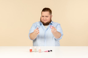 Big man looking attentively at hair bands he's holding