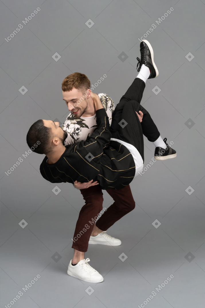 Young man smiling while holding another man bridal style