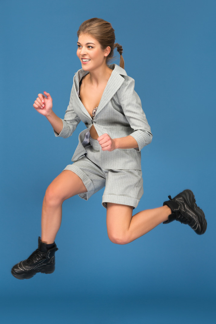 Smiling young woman jumping sideways