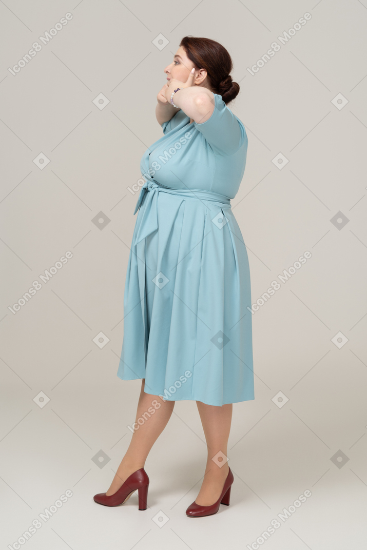 Side view of a woman in blue dress touching her mouth
