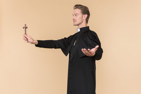 Catholic priest standing in profile and holding cross