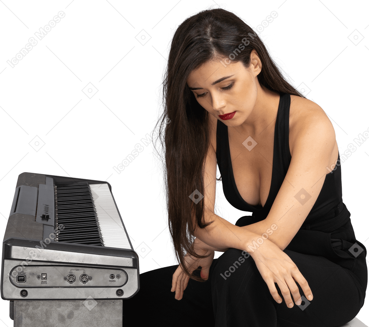 De cuerpo entero de una joven triste vestida de negro sentada junto al piano y tomados de las manos en las piernas