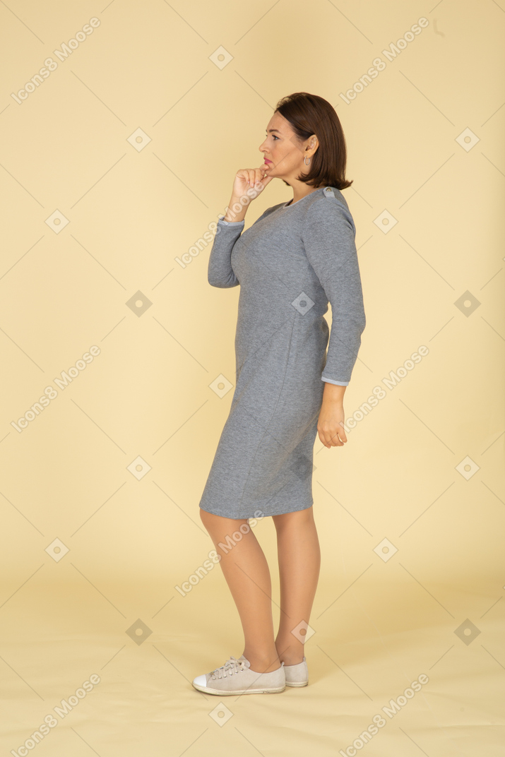 Женщина в сером платье позирует в профиль