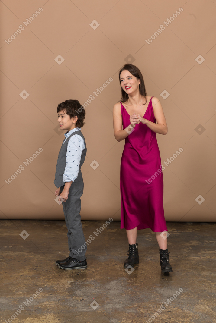 Mujer sosteniendo su propia mano y niño parado cerca de ella