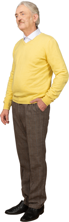 Three-quarter view of a displeased old man wearing yellow pullover and putting hand in pocket and looking aside