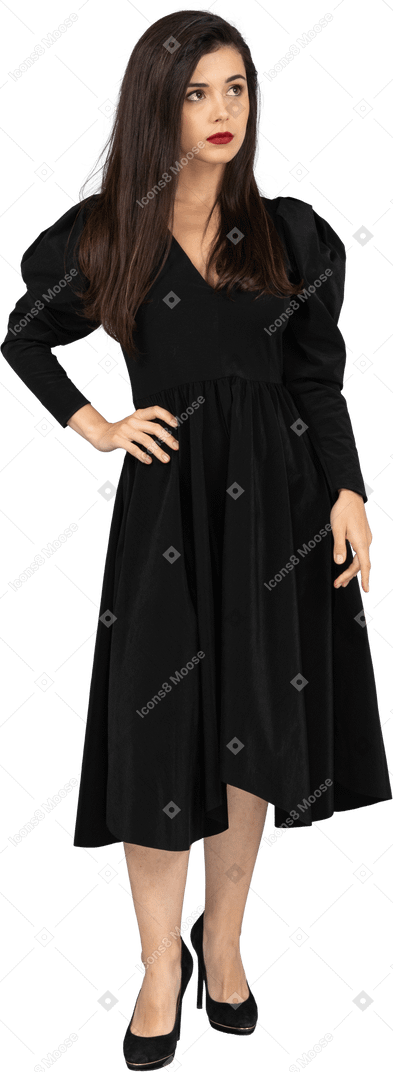 腰に手を置く黒いドレスを着た若い女性の正面図