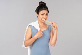 Молодая индийская женщина держит полотенце на плече и чистит зубы