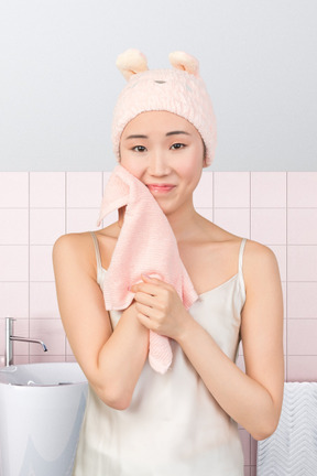 A woman in a bathroom holding a pink towel