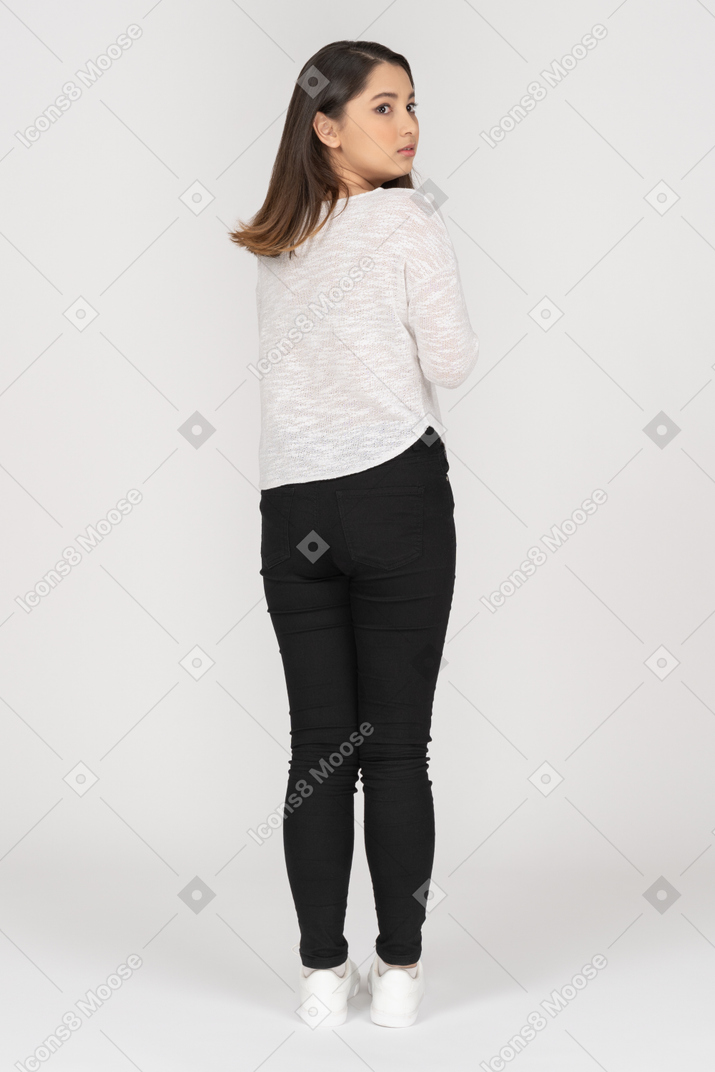 Serious young woman standing back to camera