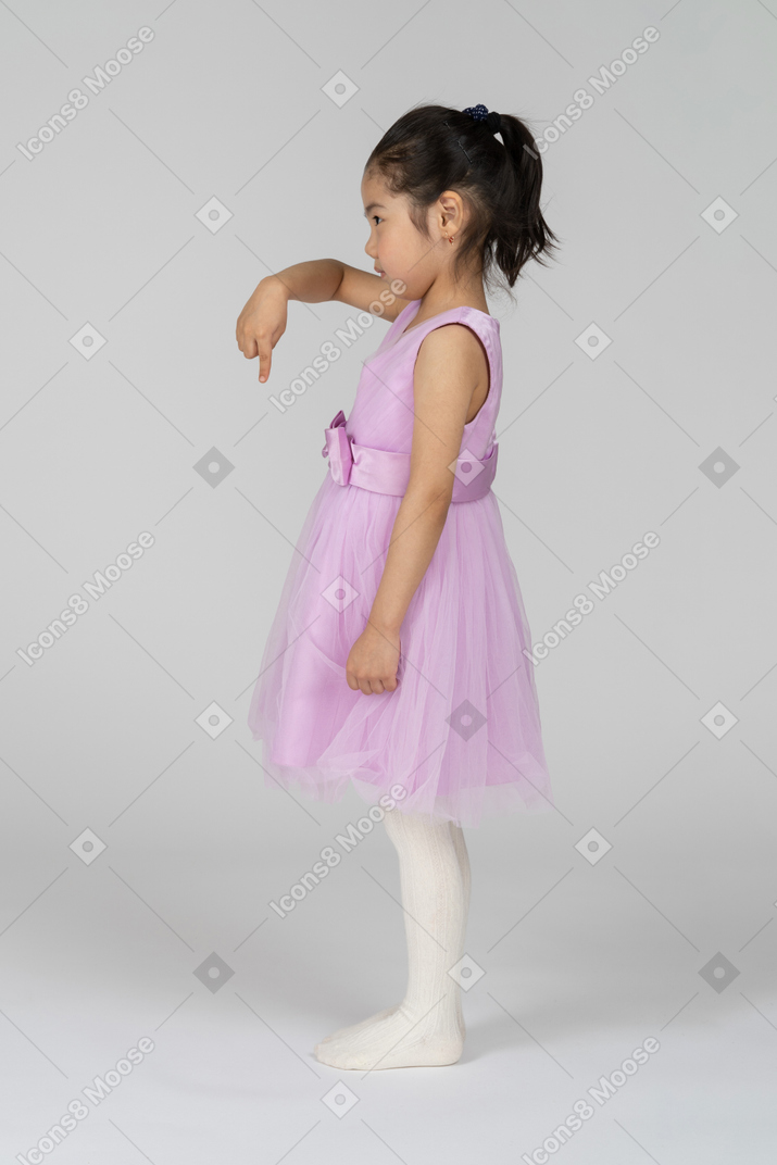 Vista lateral de una niña apuntando hacia abajo