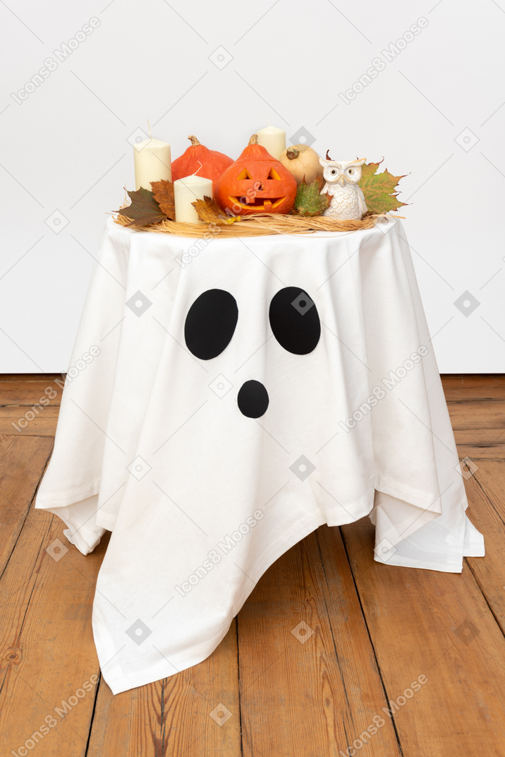Carved pumpkins and candles on white tablecloth