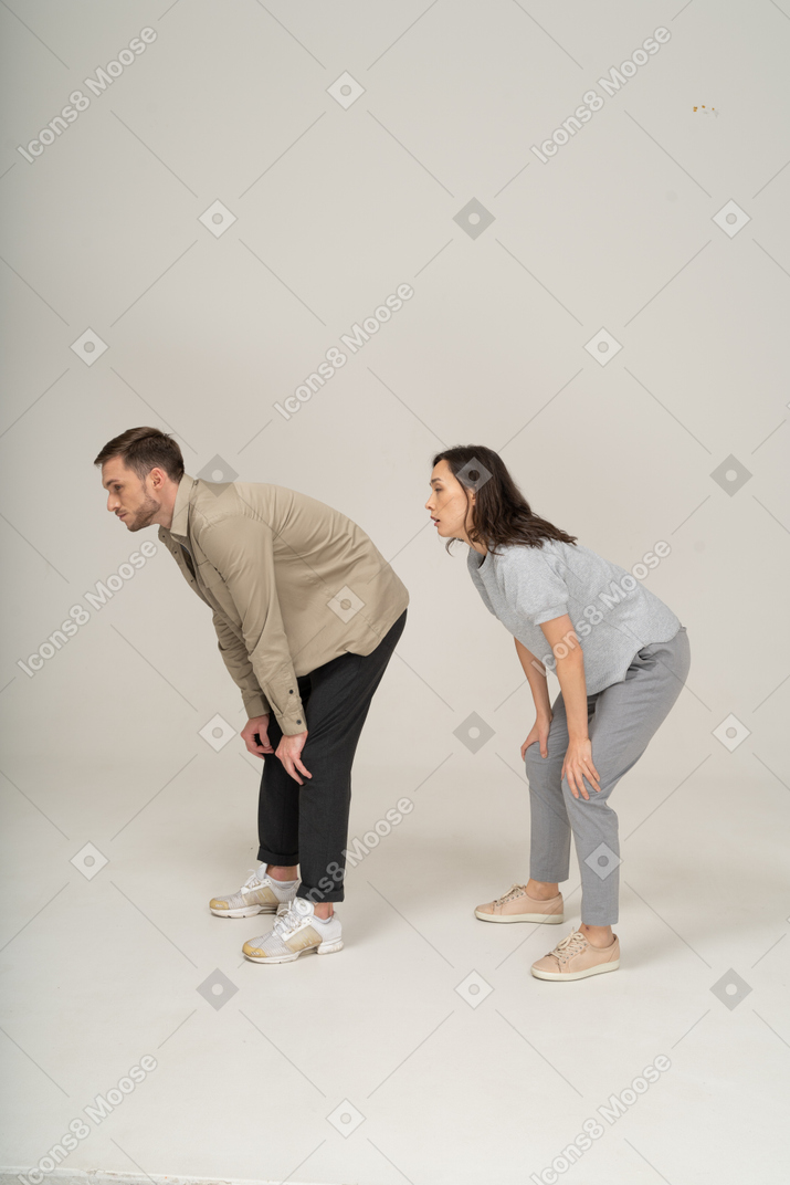 Young woman and man squatting with hands on knees