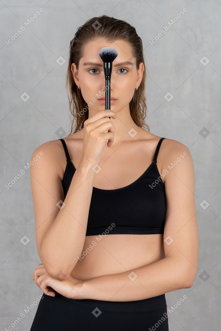 Mulher segurando um pincel de maquiagem na frente do rosto