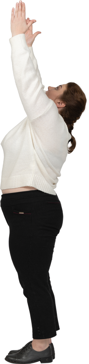 Vista laterale di una donna grassoccia in abiti casual in piedi con le braccia alzate