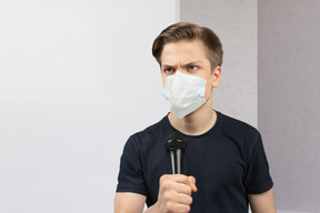 A man wearing a face mask holding a microphone