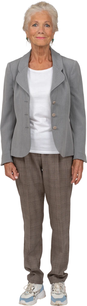 Vista frontal de una anciana en traje sonriendo y mirando a la cámara