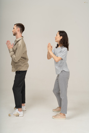 Vista lateral do homem e da mulher com as mãos em oração
