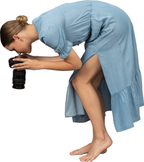 Side view of a young woman in blue dress taking shot