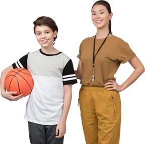 Physical education teacher standing next to pupil which is holding basketball ball