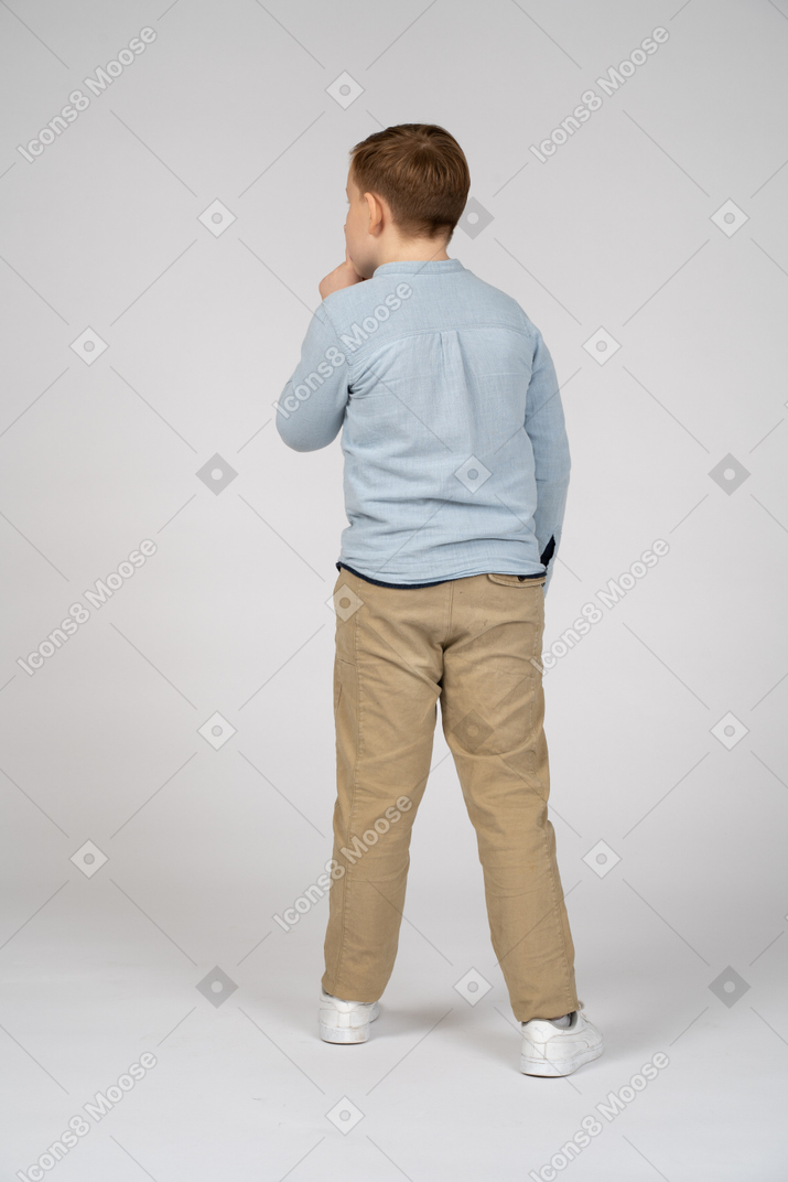 Vista traseira de um menino fazendo gesto de shhh