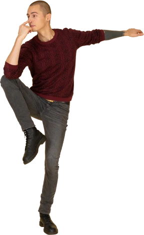 Front view of a balancing young man in red pullover touching his nose