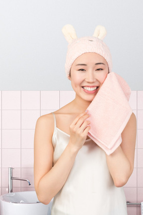 A woman in a white tank top is holding a pink towel